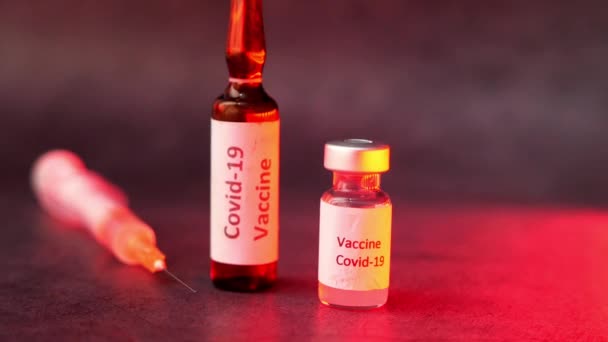 Крупним планом вакцина проти коронавірусу та шприц на чорному тлі — стокове відео
