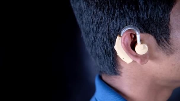 Концепция слухового аппарата, молодой человек с проблемами со слухом. — стоковое видео