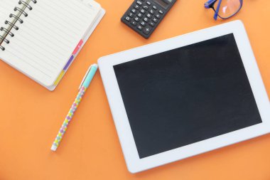 Turuncu arkaplanda dijital tablet ve ofis sabit bileşimi 