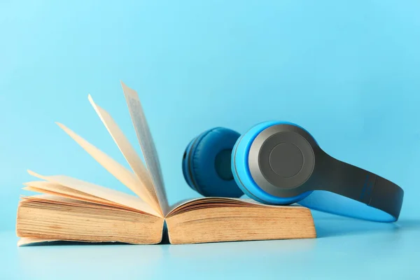 Audio book concept. Headphones and a book on blue background