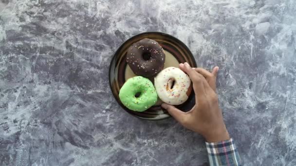 Recoger donas coloridas de un plato — Vídeo de stock