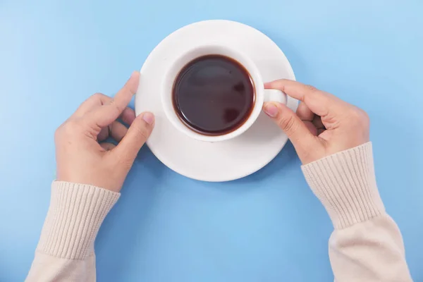 Mão segurando xícara de chá no fundo azul claro — Fotografia de Stock