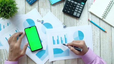 çubuk tablosunu analiz eden ve akıllı telefon kullanan bir adamın düz kompozisyonu 