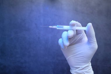 Doktor elinde şırınga tutan tıbbi eldivenler getirdi..