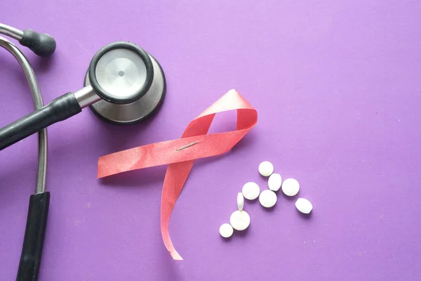 Red ribbon HIV, and stethoscope on purple background. — Stock Photo, Image
