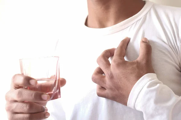 Hombre sosteniendo un vaso de agua y sufriendo dolor de corazón — Foto de Stock