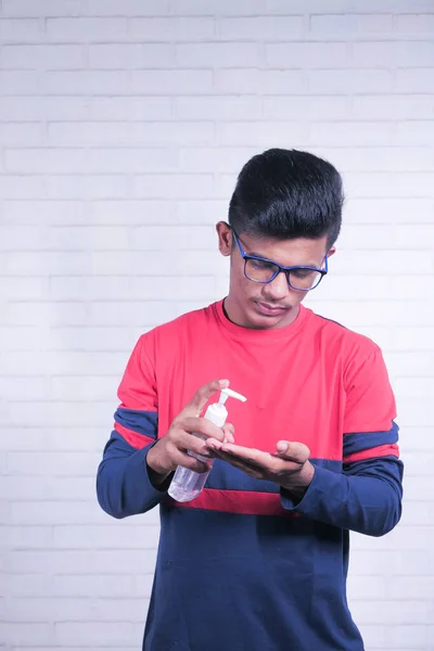 Genç Asyalı adam korona virüsünü önlemek için dezenfektan sıvısı kullanıyor. — Stok fotoğraf