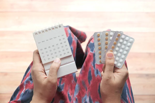 Vrouwen hand houden anticonceptiepillen en kalender — Stockfoto