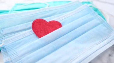 Kalp şeklinde cerrahi maskeler ve beyaz arka planda el dezenfektanı. 