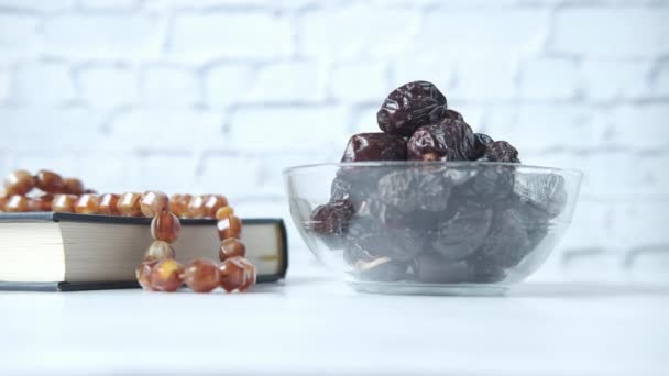 Hand plukken vers date fruit in een kom en heilig boek van de koran op tafel — Stockvideo