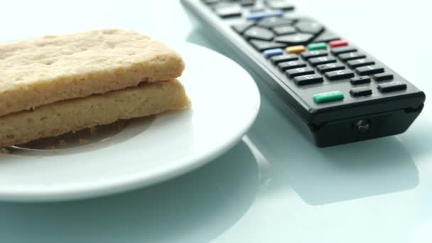 Cookies y control remoto de televisión en el fondo de color . — Vídeo de stock