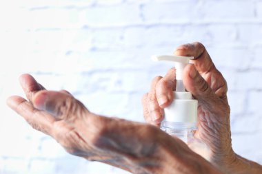 Virüsü önlemek için dezenfektan jeli kullanan yaşlı kadınların ellerini kapatın 