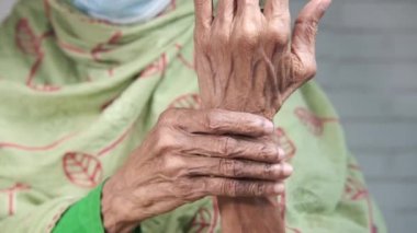 Yaşlı Asyalı kadın bilek ağrısı çekiyor. 