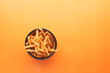 Turuncu arka planda patates cipsli kase. .