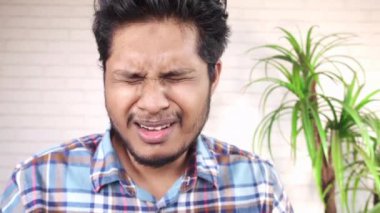 Genç hasta adam burnunu ve ağzını koluyla kapatıyor..