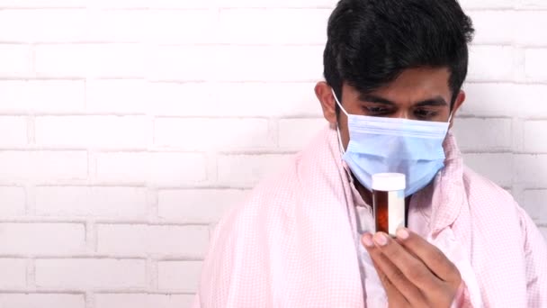 Młody mężczyzna w chirurgicznej masce do twarzy trzymający pojemnik na pigułki — Wideo stockowe