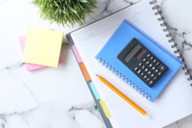 Arkaplandaki karoların üzerine hesap makinesi ve not defteri 