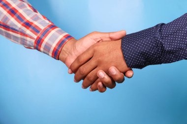 İki kişi el sıkışırken mavi arka plan,