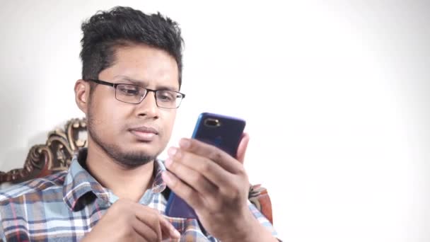 Азіатський молодий чоловік рука за допомогою смартфона, що сидить на дивані — стокове відео