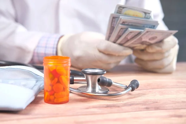 doctor hand counting cash with pill container on table