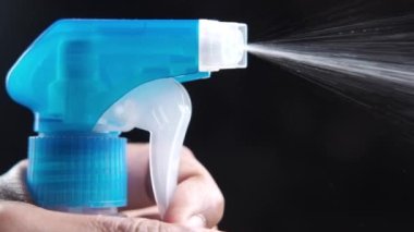 Sprey şişesinden dökülen sıvı siyah üzerine izole edilmiş. 