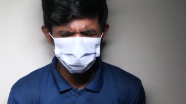 Grip olmuş hasta bir adam, burnunu peçeteyle siliyor..