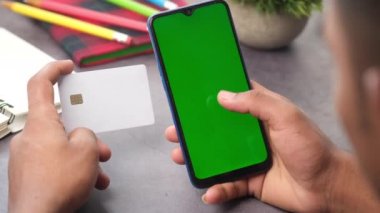Adamın biri kredi kartını tutuyor ve online akıllı telefon alışverişi yapıyor. 