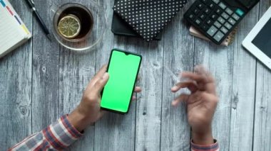 Ofis masasında akıllı telefon kullanan adamın üst görünümü hayal kırıklığını gösteriyor. 