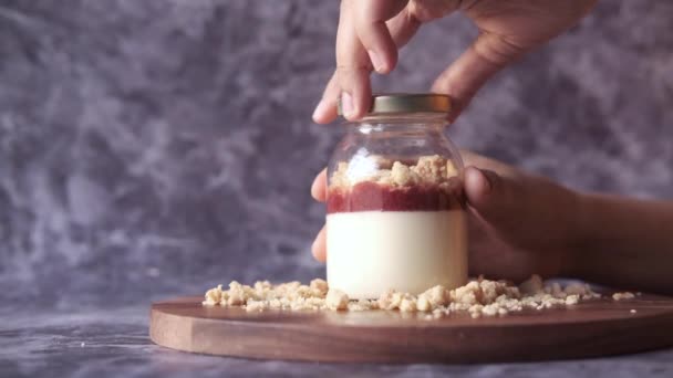 Frauenhand öffnet ein Glas Erdbeerkäsekuchen Parfait — Stockvideo