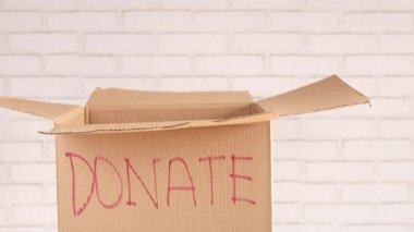 Eski kıyafetleri bağış kutusuna koyan bir bağış kutusu. 