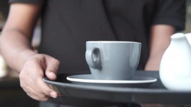 Garson kafede çay ya da kahve servisi yapıyor. ,