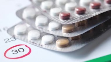 Tahta arka planda doğum kontrol hapları ve takvim, kapatın. 