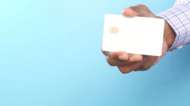 Adamın elinde mavi arka planda kredi kartı görünüyor. 