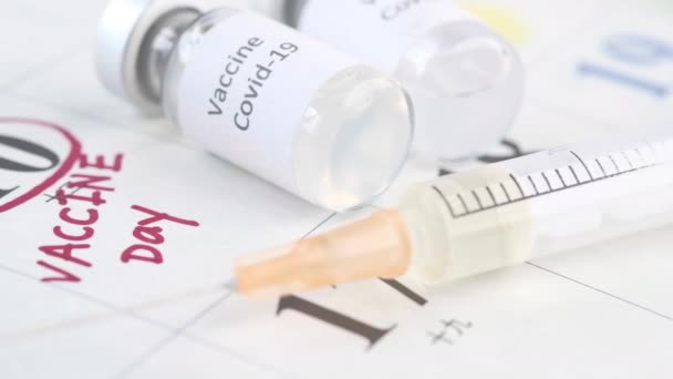 Vakcinační den koncept skleněná ampulka s vakcínou a injekční stříkačkou v kalendáři — Stock video