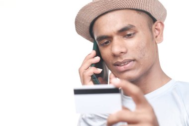 Elinde kredi kartı olan ve telefonla konuşan bir adam beyazda izole edilmiş. 