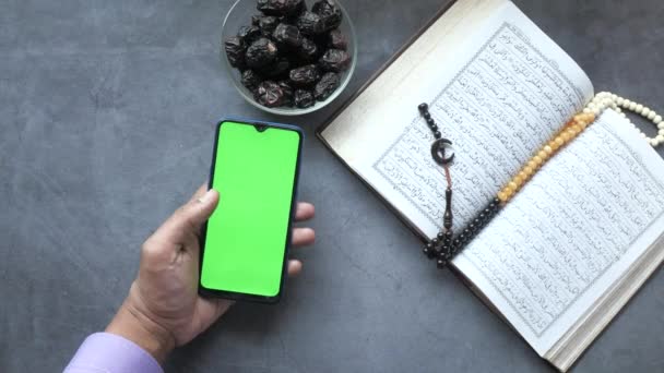 Met behulp van smart phone, Heilige boek Koran en rozenkrans op tafel, — Stockvideo