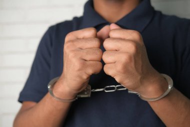 Siyah gömlekli, kelepçeli bir adam. 