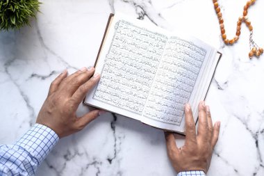 Müslüman adam el yordamıyla Kuran okuyor. 