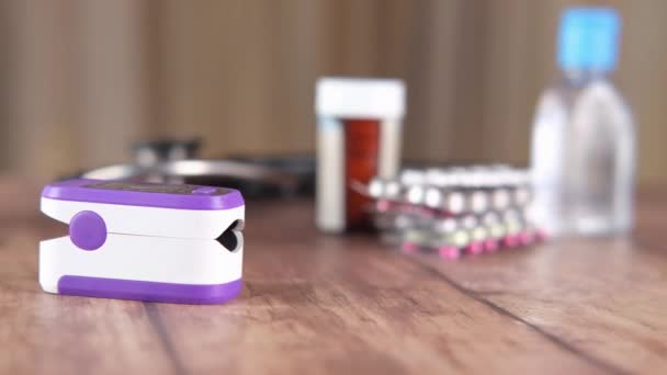 Oxímetro de pulso y pastillas contenedor en la mesa — Vídeos de Stock