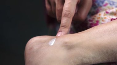 Kadın ayaklarına güzellik kremi sürüyor. Yakından. 