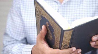 Elinde kutsal kitap Kuran 'ı tutan adam. 