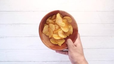 Elinde bir kase lezzetli patates cipsi var. 