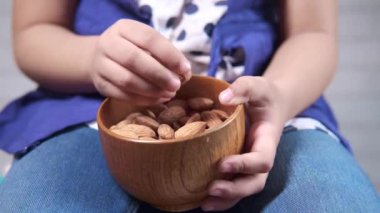 Elleri bademde bir kase tutan kız çocuğu. 