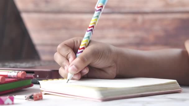 Κοντινό πλάνο του παιδιού κορίτσι χέρι γράφοντας στο σημειωματάριο. — Αρχείο Βίντεο