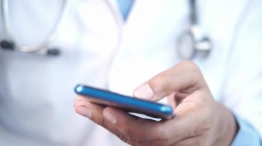 Beyaz önlüklü doktor akıllı telefon kullanıyor..