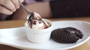 Kadınlar ellerinde kaşıkla kafe masasında dondurma yiyorlar. 