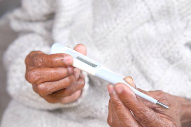 Dijital termometreyi tutan yaşlı kadınların fotoğraflarını çek.