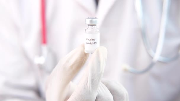 Hand in hand latex handschoenen met glazen ampul vaccin, met kopieerruimte — Stockvideo