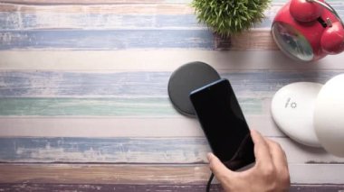 Man Hand kablosuz şarj pedi kullanarak akıllı telefonu şarj ediyor. 