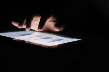 Adam el ile ofis masasında dijital tablet üzerinde çalışıyor, kendi yarattığı grafiği kullanarak. 